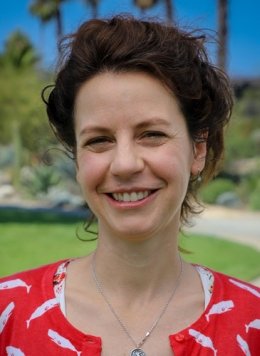 Closeup of Ashley Heers, who has wavy dark brown hair that is pulled up and wears a red top with a white print pattern of whales.