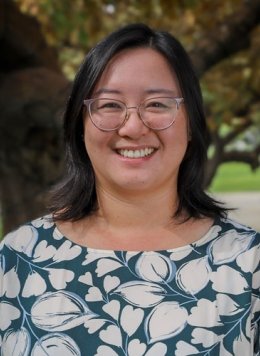 Closeup of Lisa Yin Han, who has shoulder-length straight black hair and wears glasses and a blue top with white floral print.
