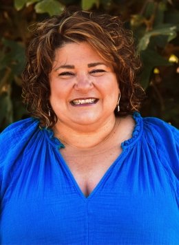 Woman with short brown hair wearing blue blouse.
