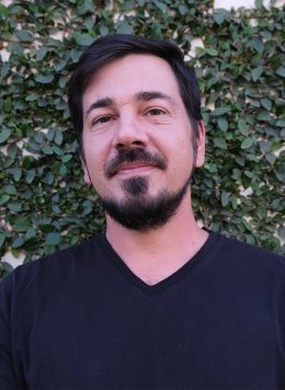 Man in black top with short black hair and beard.