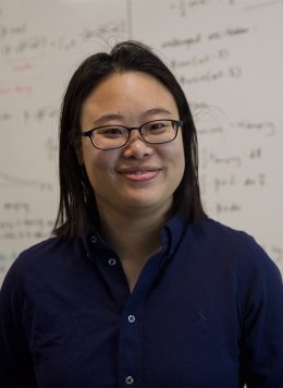 Woman in black top wearing glasses with black short hair.