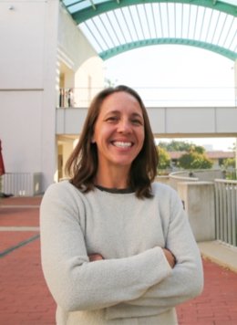 Woman in short brown hair wearing white sweater.
