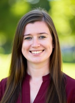 Woman wearing maroon blouse with long brown hair.