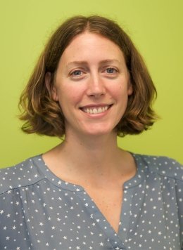 Woman wearing blue polka dot blouse with short brown hair.
