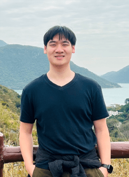 Man wearing black shirt with short black hair posing in front of mountain view point.