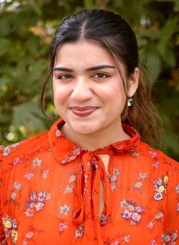 a student with long brown hair pulled back into a pony tail wears a orange blouse with a flower print