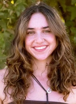 head shot of Samantha Berman standing in front of outdoor greenery