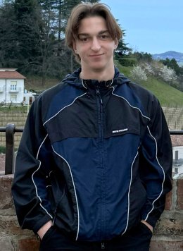 a boy in a blue and black jacket in front of a brick wall
