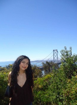 A girl standing in front of a view of the golden gate bridge