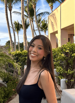 a girl smiling at the camera with palm trees in the background