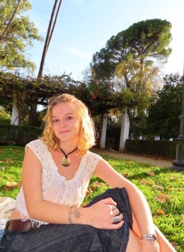 a girl in a white top sitting on the grass