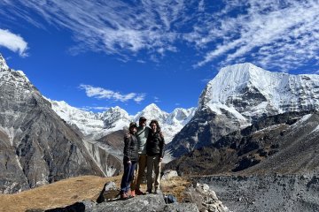 3 students stand in front of mountains in Nepal
