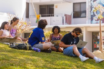 a group of students sits on the mounds in front of mead hall