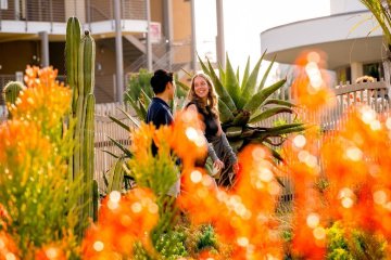 two students walk with colorful flowers in the foreground
