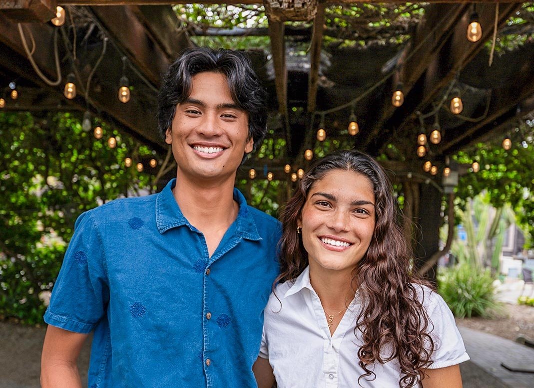 Sammy Basa and Zhane Moledina stand together under the leafy green canopy of Pitzer’s Grove House Outdoor Classroom.