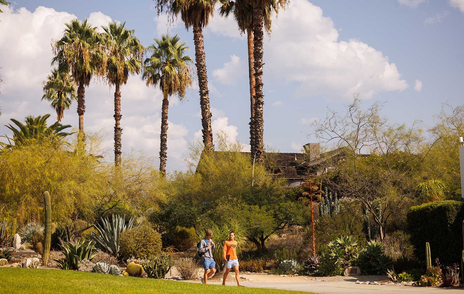 two student walk in front of the grove house  on a sunny day