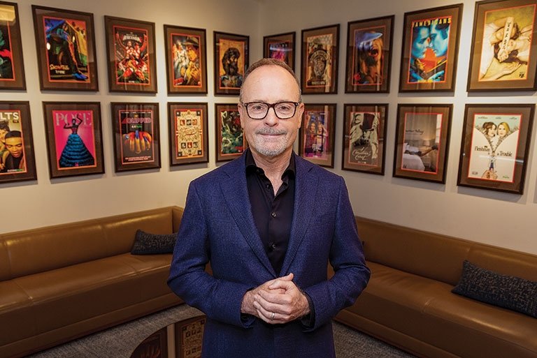 John Landgraff stands in a room decorated with tv posters