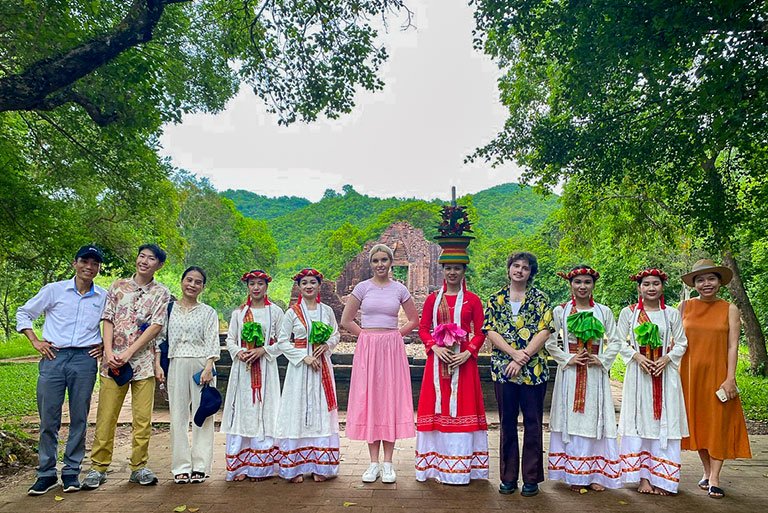 Pitzer students pose with women in traditional Vietnamese dresses