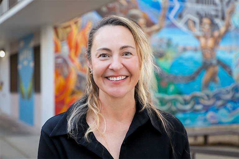 Jessica McCoy stands in front of a mural in the Mead Hall Courtyard