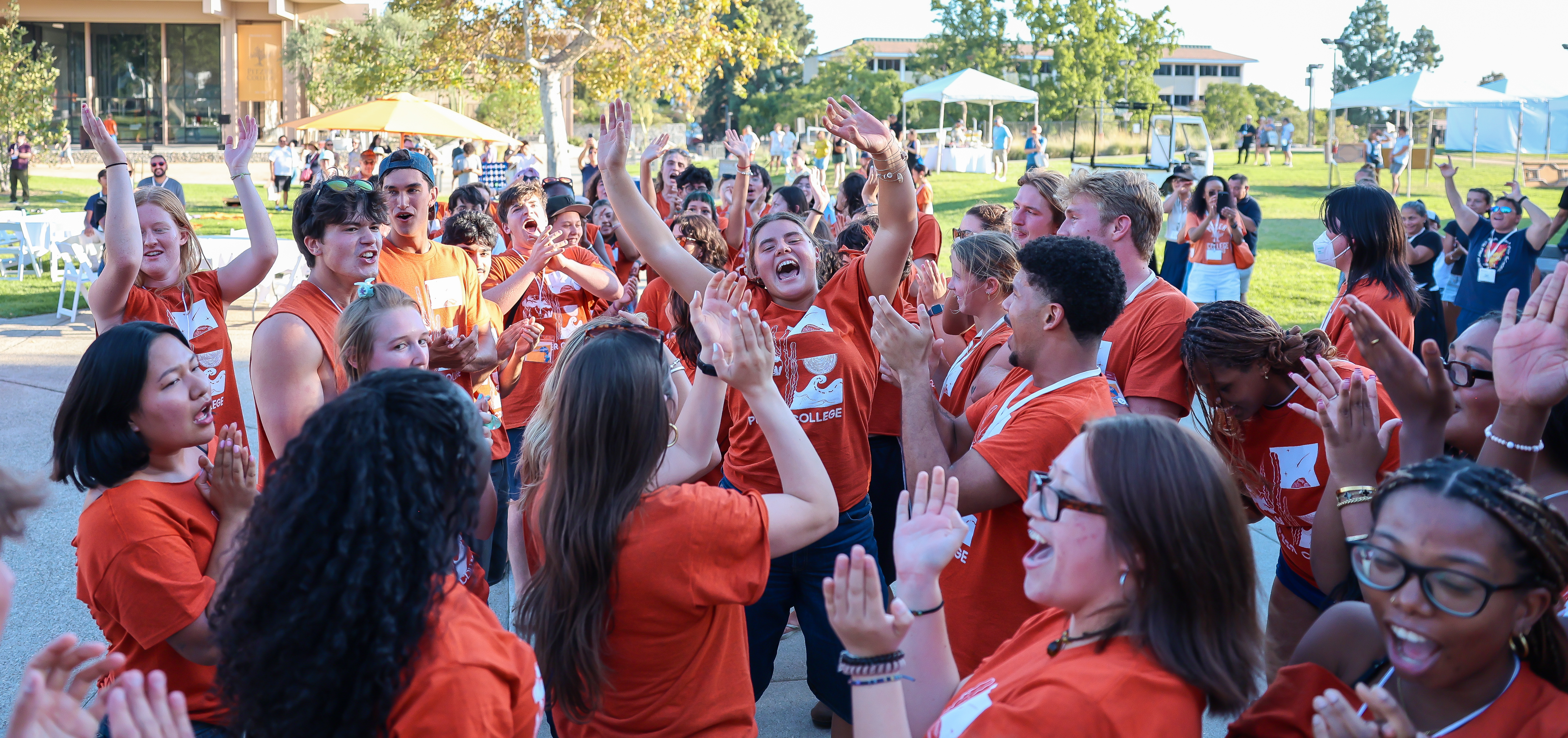 a group of students in orange shirts cheering