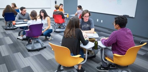 Students discuss in groups of three in a classroom