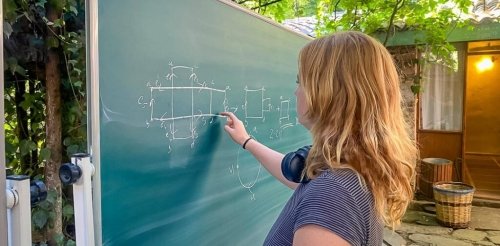 student solves math problem on an outdoor blackboard