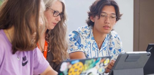 two students study with a faculty member