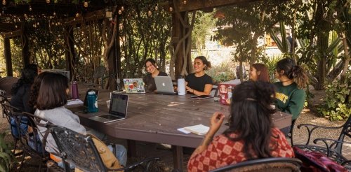 Students talk and work in an outdoor classroom by the Grove House
