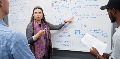 Professor Bahar Acu explains a concept as two students look on