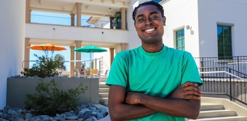 richard ampah wears a green tshirt and poses in front of the nucleus west building