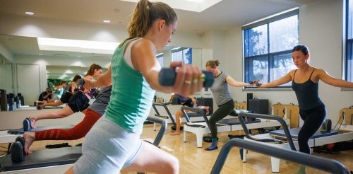 students participate in a pilates group class at the gold student center