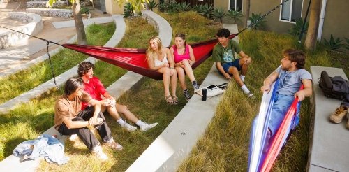 students sit in hammocks and on concrete benches in a dorm quad