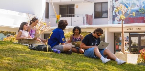 a group of students sits on the mounds in front of mead hall