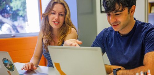 two students works at a desk in an office