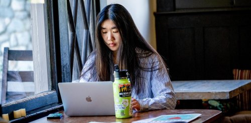 a student works at a laptop in the grove house living room