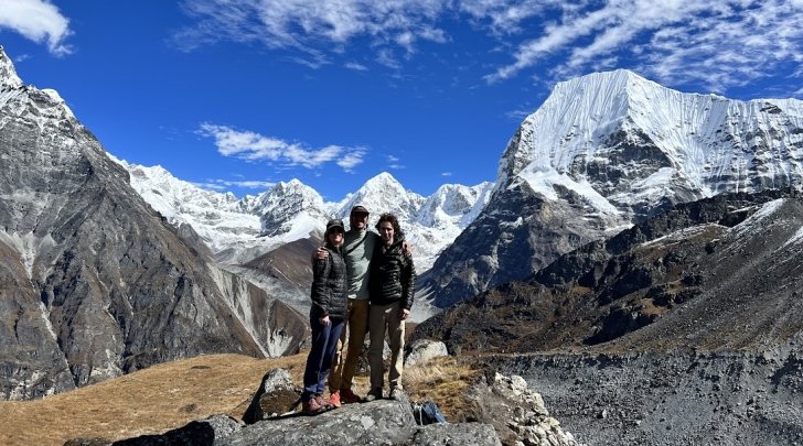 3 students stand in front of mountains in Nepal
