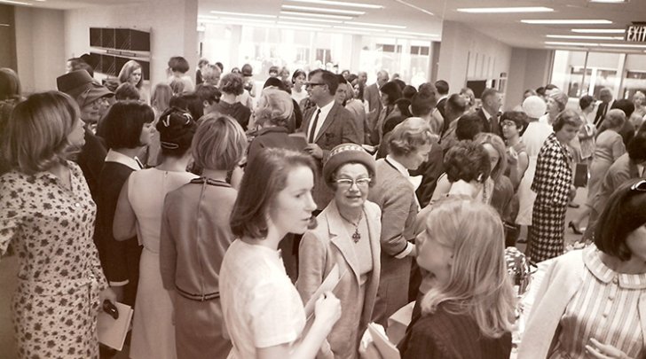 Crowd of people inside building talking to each other in 1966.