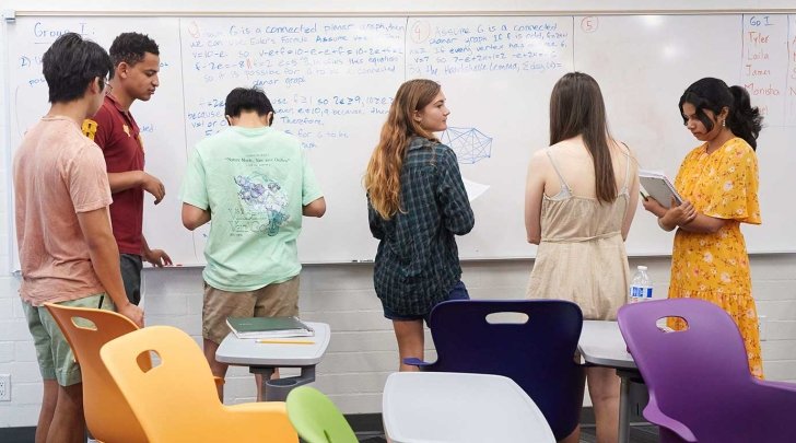 Students writing on the board in classroom