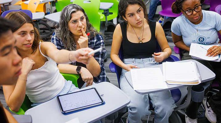 students sit in a desk and point at something off in the distance
