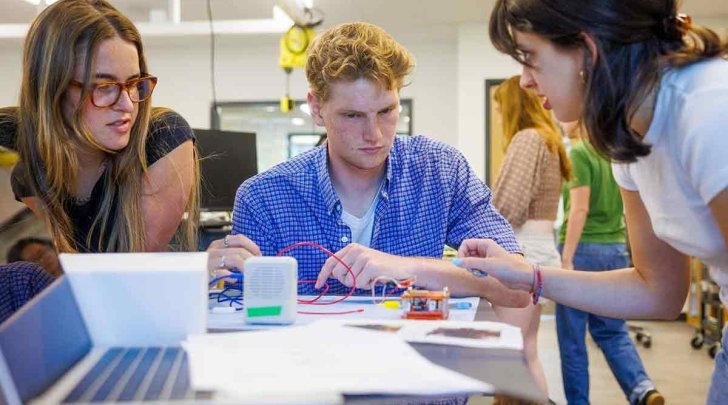 three students work on a project together in a physics lab