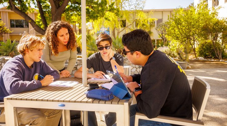 Pitzer students review assignments with a professor outside the Pit Stop Cafe