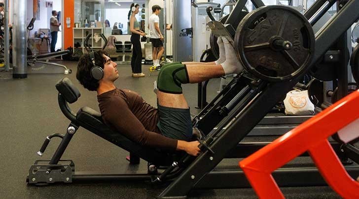 a student works on a leg machine at the Gold Student Center gym