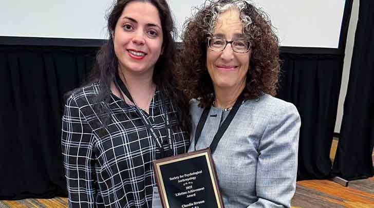 claudia strauss poses with an award while standing next to a colleague