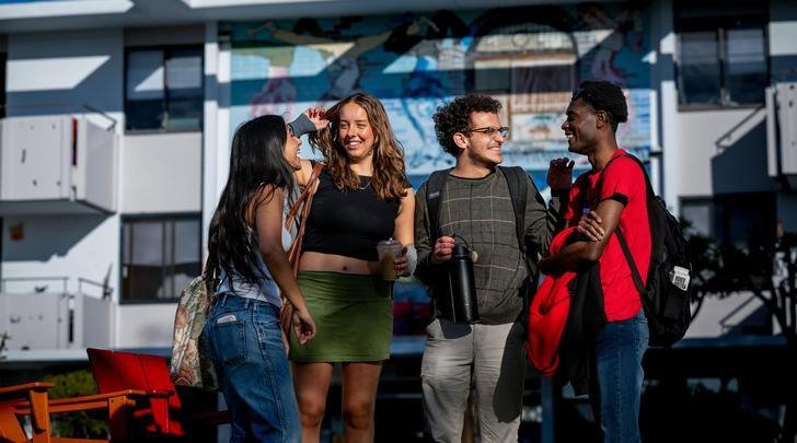 a group of students chat in front of Mead Hall