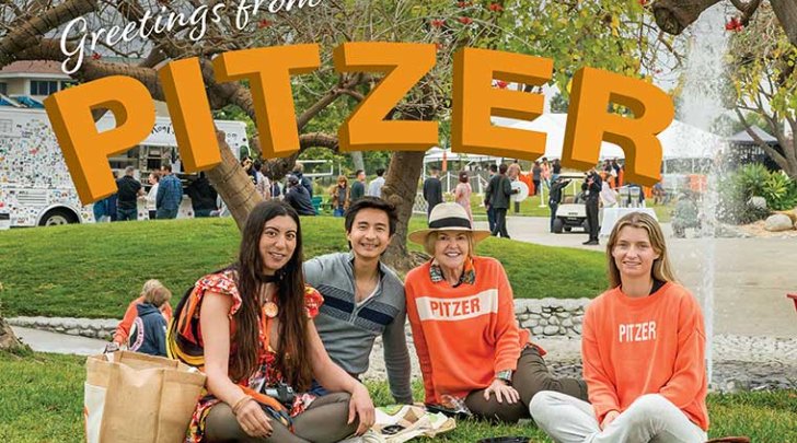four alumni sit on the mounds with the fountain behind them with the words "Greetings form Pitzer" above them in orange