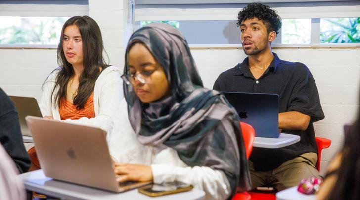 three students sit in a class room