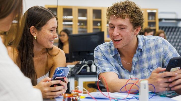 two students sit at a table in a classroom