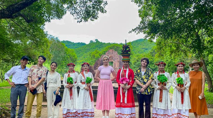 Pitzer students pose with women in traditional Vietnamese dresses