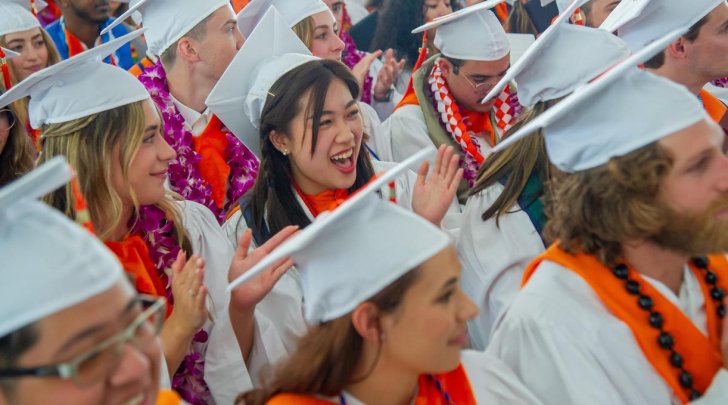 students in graduation gowns and hats cheer