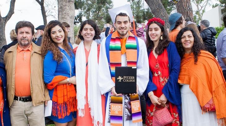 a graduate poses with his family on the mounds